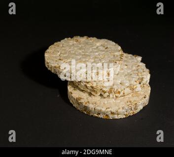 Grain crispbreads crispy rice and diet bread. Stack of puffed whole grain crispbread. Rice cake puffed rice on black background Stock Photo