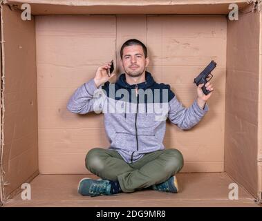an unemployed man orders a ransom, gun in hand and talking on the phone Stock Photo