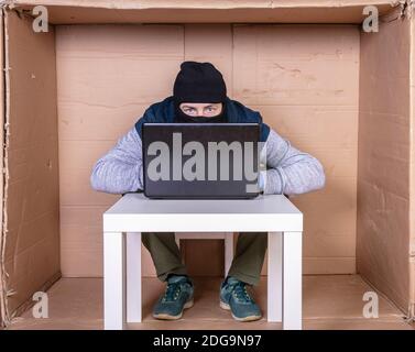 hacker covers his face while working on a computer Stock Photo