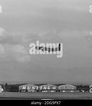 Archival monochrome image of a Vickers Vanguard 953C Merchantman airliner in British Airways Cargo livery in the air at Heathrow Airport, London, 1979, with a view of Hunting-Clan Air Transport hangar, demolished 1986. Possibly G-APEP 'Superb' now at Brooklands Museum Surrey England. Alternative crop 2JF3A1E Stock Photo
