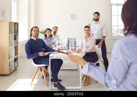 Group of office workers sitting and listening to colleague making presentation in office Stock Photo