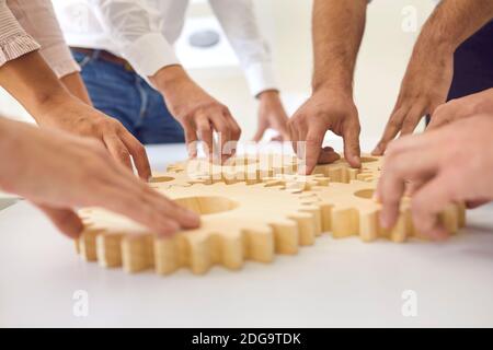 Hands of business people making whole picture of wooden gears on table together Stock Photo
