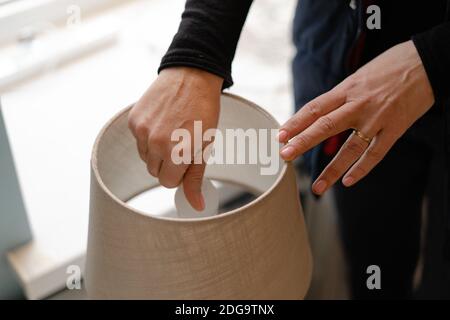 Woman hand replacing light bulb for energy saving one. Energy efficiency at home Stock Photo