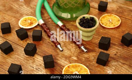 Tobacco in the bowl for hookah on wooden background with coal