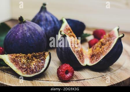 A few cuted figs and red berries on a plate on an old wooden background Stock Photo