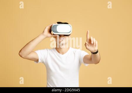 Man in vr glasses playing games with virtual reality headset trying to touch something with finger Stock Photo