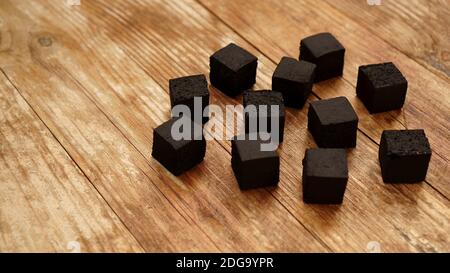 Cubes of coconut coal for hookah on wooden background. Place for text Stock Photo