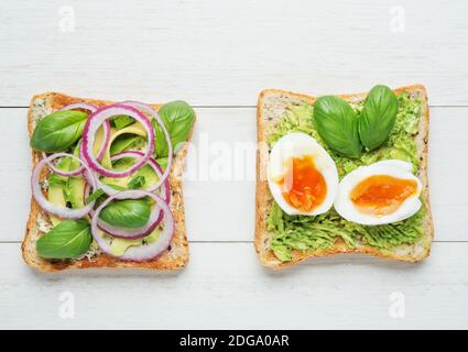 Two avocado toasts on white wooden background Stock Photo