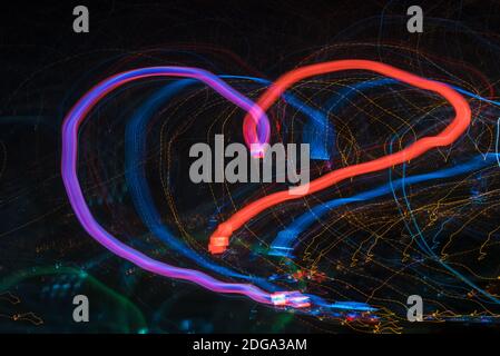 Bright glow abstract heart shaped patterns from light strips on a black background Stock Photo