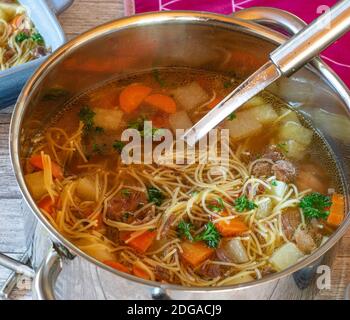 a pot with beef noodle soup from above with ladle Stock Photo