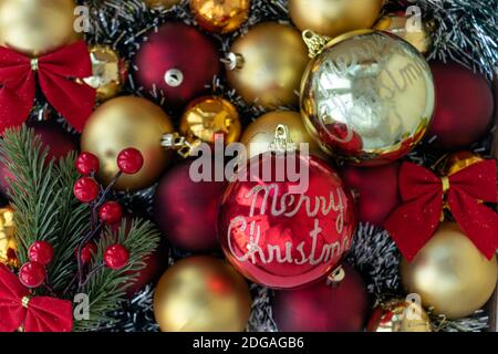 Gold and red Christmas balls with red bows. Big red Christmas ball with words Merry Christmas. Christmas background. New Year or Xmas concept. Top vie Stock Photo