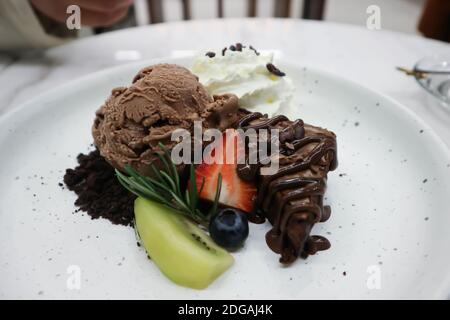 brownie , chocolate ice cream with whipping cream and fruit Stock Photo