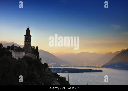 Church Tower on the Mountain Peak over an Alpine Lake Maggiore in Dusk in Ronco sopra Ascona in Ticino, Switzerland. Stock Photo