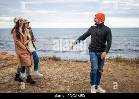 Three mixed-race carefree friends walking outdoor joking each other - Young multiracial people having fun outdoor smiling in winter vacation living th Stock Photo