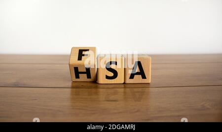 FSA or HSA symbol. Turned a cube and changed the word 'FSA - Flexible Spending Account' to 'HSA - Health Savings Account'. Beautiful wooden table. Whi Stock Photo