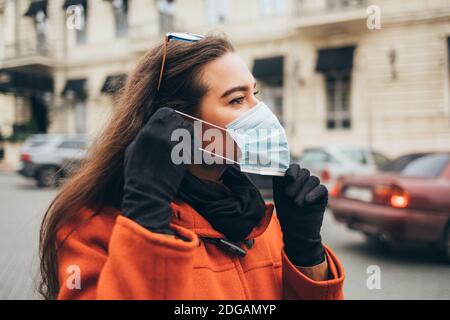 Young woman wearing a medical mask in the city in autumn Stock Photo