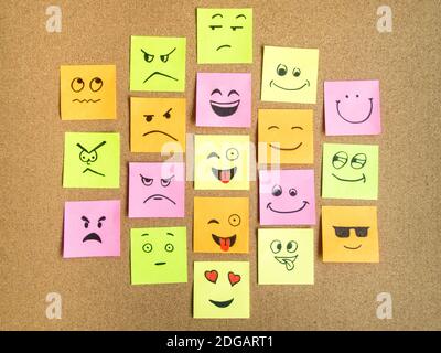 cork board with colorful post its representing various emoticons with various emotions communication concept Stock Photo
