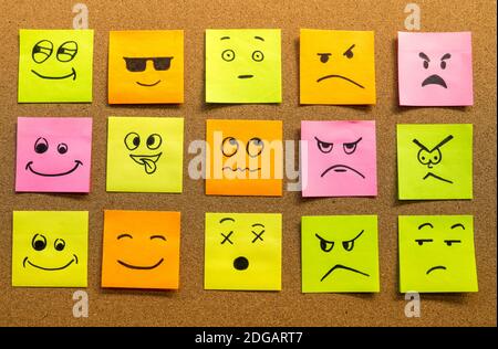 cork board with colorful post its representing various emoticons with various emotions communication concept Stock Photo