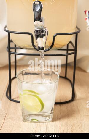 https://l450v.alamy.com/450v/2dgattn/mans-hand-pouring-a-glass-of-citrus-juice-into-a-beverage-dispenser-operate-the-valve-to-close-and-open-the-tap-of-the-juice-bottle-2dgattn.jpg