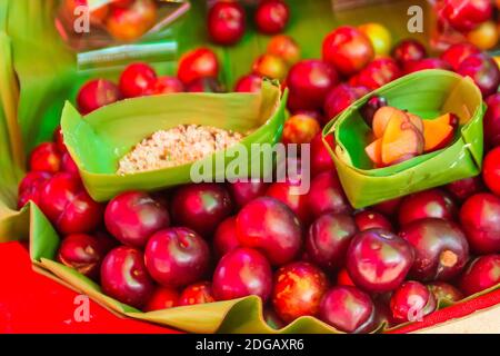 Red ramontchi fruits (Flacourtia indica) for sale at the local market in Chiang Rai, Thailand. Flacourtia indica also known as ramontchi, governor’s p Stock Photo