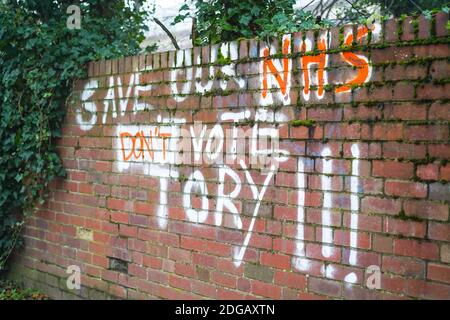 Graffiti in spray paint on outdoor garden brick wall in England, UK, saying 'Save Our NHS, Don't Vote Tory'. Political statement vandalism. Stock Photo