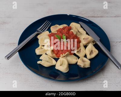 Vegetarian dumplings on a plate with tomato sauce, wooden background, top view, free space for text Stock Photo