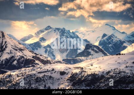 Snowy mountains is lighted by sunbeam at sunset in winter Stock Photo