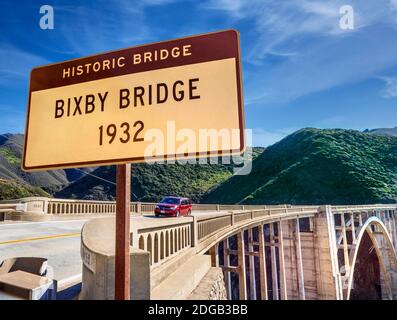 BIG SUR BIXBY BRIDGE Highway sign 1932 on Highway 1, with bridge and red touring car crossing behind at Bixby Creek Bridge, Big Sur, Monterey, California USA Stock Photo