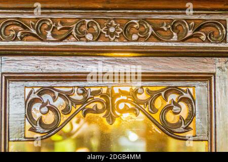 Beautiful patterned on wooden door frame in Thai style carved. Carving pattern of vine and flower in the traditional Thai style on the wooden door of Stock Photo