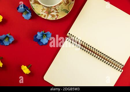 Flat design photo on red background with place for text, decorative flowers, blank notepad, top view, beautiful composition Stock Photo