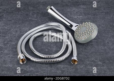 Showerhead and flexible connection hose close-up on grey shabby background Stock Photo