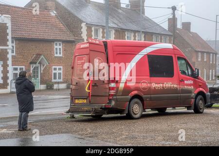 Woman queuing for mobile post office on a foggy winter day in Snettisham, Norfolk. Stock Photo