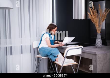 Woman on remote work or online education, using laptop computer, making notes, indoors at home. Online business, young professional at workplace Stock Photo