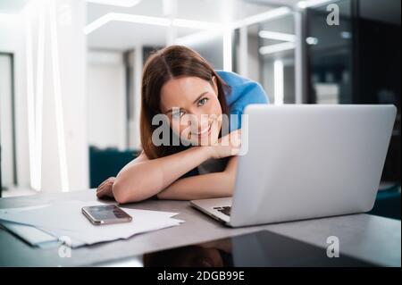 Portrait of happy successful caucasian woman in informal wear looking and smiling at the camera. Attractive female manager on self isolation after Stock Photo
