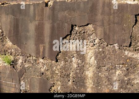 Weathered wall of heavy concrete aggregate, crumbling stucco skim coat, dirty brown patina, creative industrial copy space, horizontal aspect Stock Photo