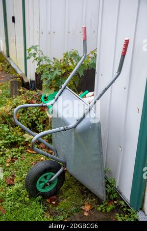 Aluminium wheelbarrow against garden shed Stock Photo