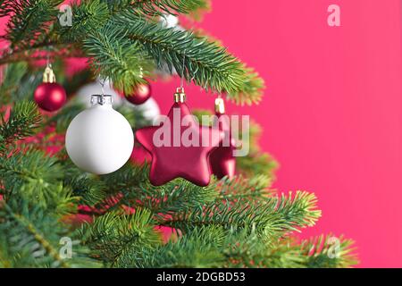 Close up of decorated Christmas tree with pink star shaped and white ball shapedl tree ornament baubles on pink background Stock Photo