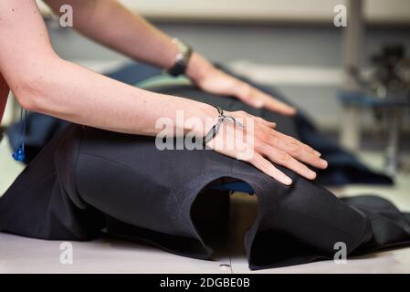 Ironing table. Industrial Presser in sewing suit clothes pressed. Stock Photo