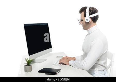 Cyborg in headphones using computer with blank screen near plant and notebook on table isolated on white Stock Photo