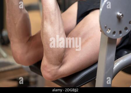Man flexing isquiotiobial leg muscles on leg curl gym machine. Sport, fitness, bodybuilding and people concept. Stock Photo