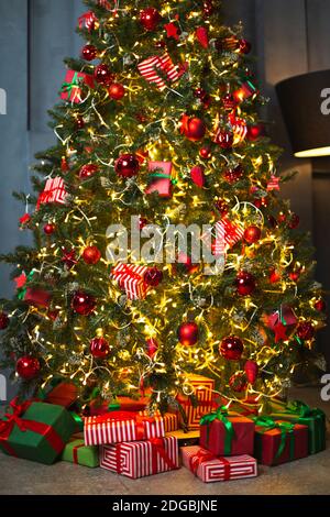 From above bunch of colorful gift boxes placed on tiled floor under decorated coniferous tree on Christmas eve Stock Photo