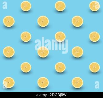 Repeated seamless pattern of many sliced ripe lemons on light blue background. Stock Photo