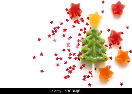 Star shaped fruit jelly, red star shaped confetti and green fir tree shaped lollypop on white background. Top view with space for your text Stock Photo