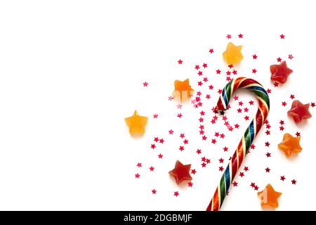Star shaped fruit jelly, red star shaped confetti and colorful candy cane on white background. Top view with space for your text Stock Photo