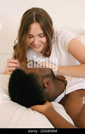 Mixed race couple lying in bed talking in the morning Stock Photo