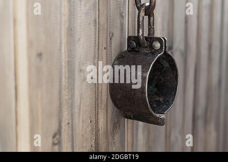 Old rusty and forged shackles closeup hanging on a wooden wall Stock Photo