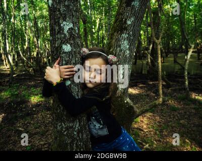 Portrait of a girl hugging a tree in the forest, Italy Stock Photo