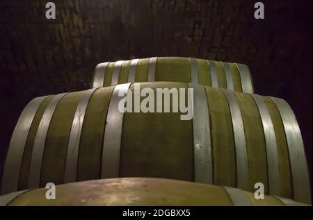Wine barrels from hard wood strapped with steel hoops stacked in a dark cellar winery Stock Photo