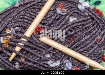 Knitting needles and a ball of woolen thread on a dark gray wooden background. dark wooden threads and knitting needles Stock Photo