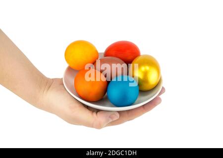 Multicolored eggs and golden lie on a ladle in a ceramic saucer on a white background Stock Photo